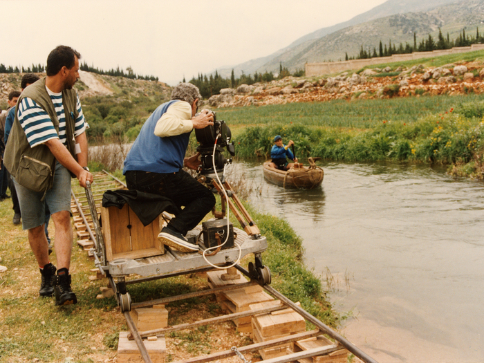 Photographie de tournage « Le Destin  »(1996) © Photo Michel Y. El Esta. Youssef Chahine à la caméra, installé sur un chariot roulant sur des rails pour effectuer un travelling.